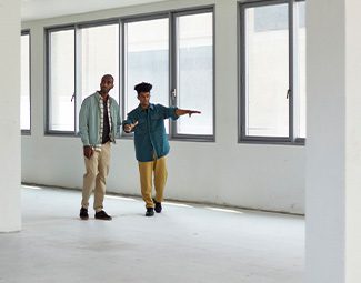Two people walking through an empty commercial office office space